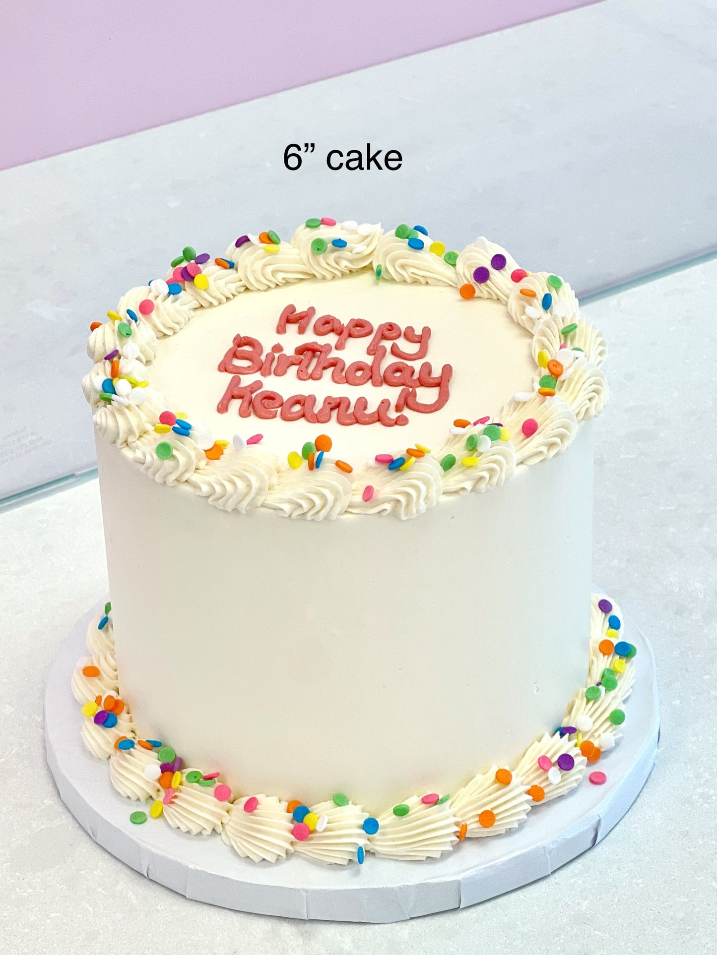 Small birthday cake with colorful sprinkles and 'Happy Birthday' text on a white surface.