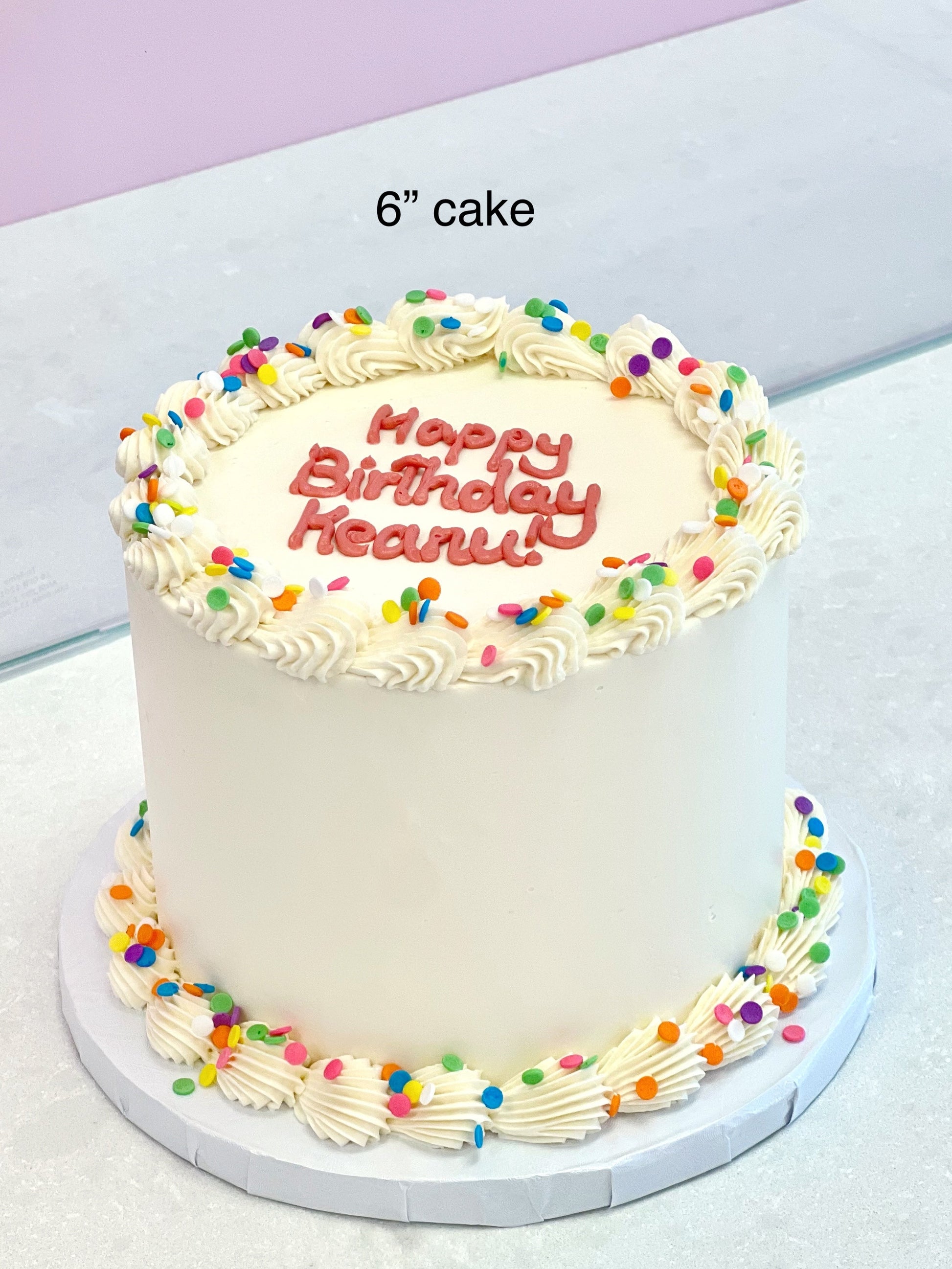 Small birthday cake with colorful sprinkles and 'Happy Birthday' text on a white surface.